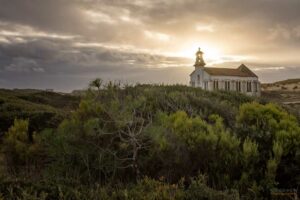 Petite chapelle sur une dune au coucher du soleil sous un ciel nuageux