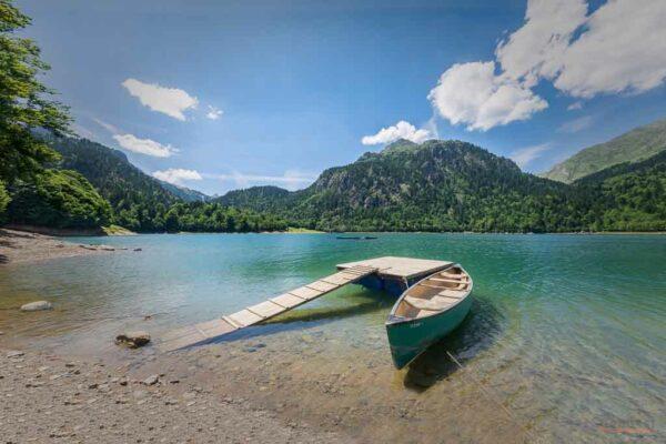 Canoë amaré sur une barge sur un lac de montagne flamboyant sous un ciel parsemé de nuages en été