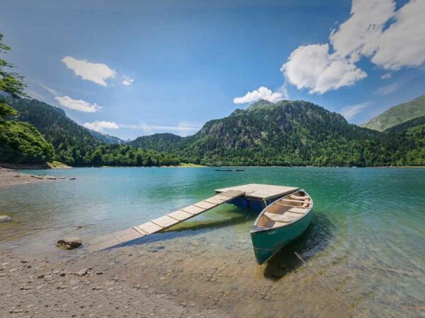 Canoë amaré sur une barge sur un lac de montagne flamboyant sous un ciel parsemé de nuages en été